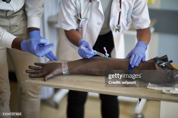 students practising injections on a phlebotomy venipuncture practise arm - iv going into an arm stock pictures, royalty-free photos & images