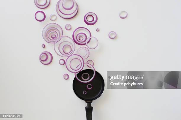 conceptual red onion ring steam over a frying pan - food flying stock-fotos und bilder