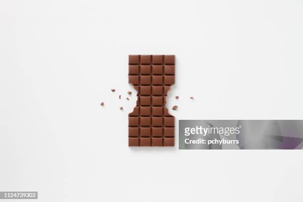 block of chocolate bar with sides bitten off and chocolate crumbs - かじりかけ ストックフォトと画像