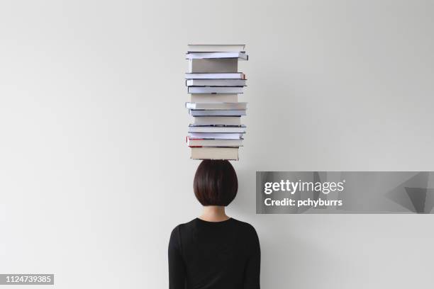 rear view of woman with stack of books on her head - 頭に乗せる ストックフォトと画像