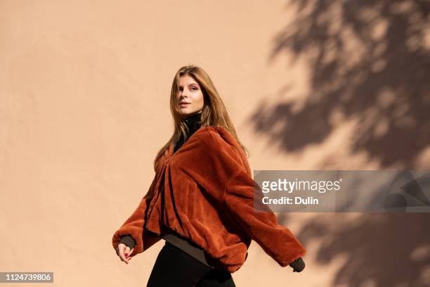 woman walking past a wall with shadow of a tree - walking side by side stock-fotos und bilder