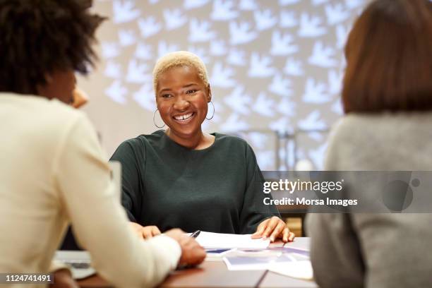 smiling entrepreneur with coworkers in office - meeting community fotografías e imágenes de stock