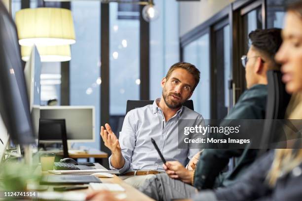 male coworkers discussing during meeting in office - startup innovation stock-fotos und bilder