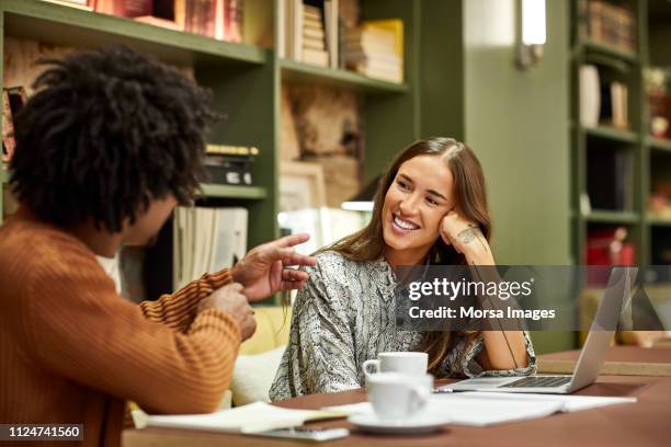 coworkers discussing at desk in creative office - luisteren stockfoto's en -beelden