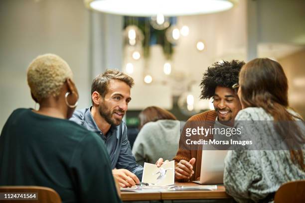 multi-ethnic coworkers discussing in office - personas reunidas fotografías e imágenes de stock