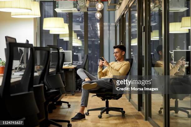 businessman using mobile phone in creative office - asian man seated stockfoto's en -beelden