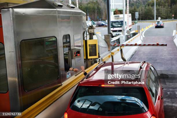stuurprogramma in rode auto betalen bij tol gate op snelweg - brennerpas stockfoto's en -beelden