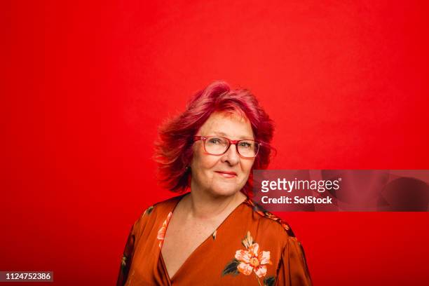 headshot of a senior woman on a red background - senior colored hair stock pictures, royalty-free photos & images