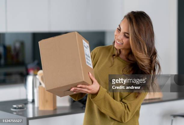 woman getting a parcel in the mail at home - opening delivery stock pictures, royalty-free photos & images
