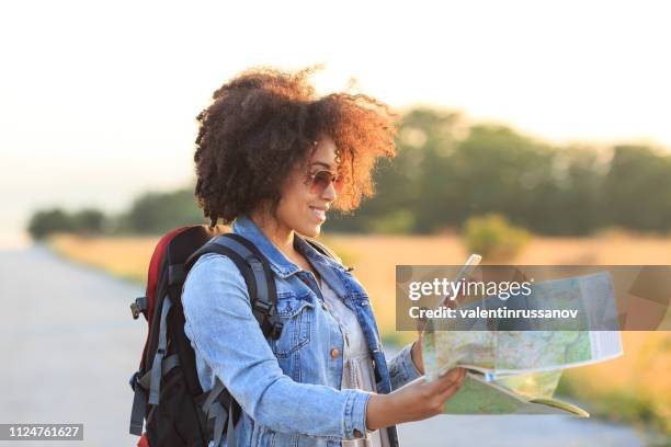 female backpacker using a map and mobile phone - woman map stock pictures, royalty-free photos & images