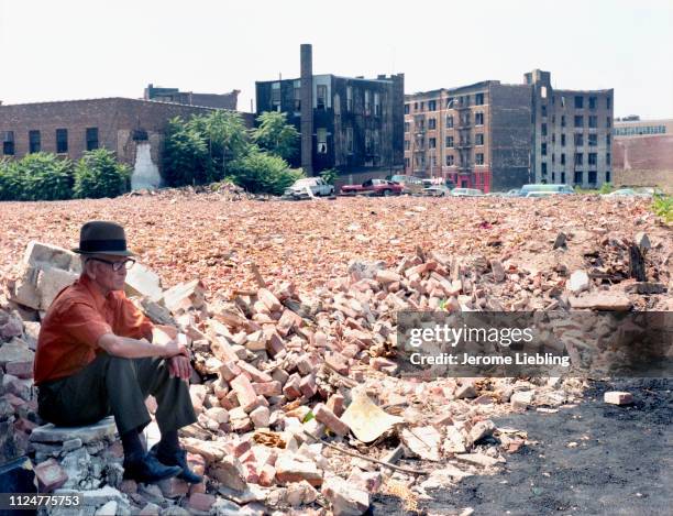 An unidentified elderly man sits among brick rubble of bombed-out tenement buildings in New York City's South Bronx neighborhood, New York, New York,...