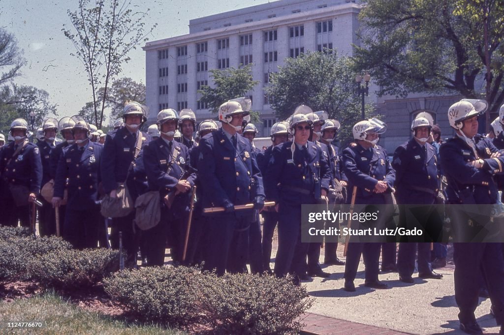 4521 Police Riot A crowd of policemen stands on a sidewalk, wearing riot helmets and ...