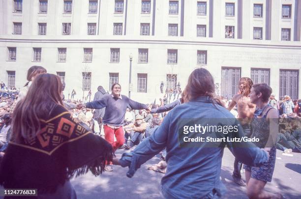 Men and women dance in a circle, holding hands, during demonstrations related to the Vietnam War May Day Protests, Washington, DC, May 1971.
