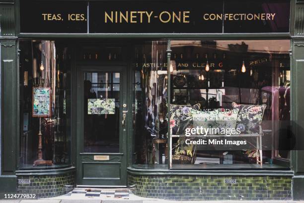 exterior view of interior design store with floral print cushions on vintage metal bench in shop window. - tienda de regalos fotografías e imágenes de stock