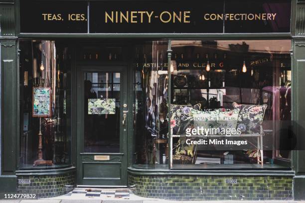exterior view of interior design store with floral print cushions on vintage metal bench in shop window. - store window stock pictures, royalty-free photos & images