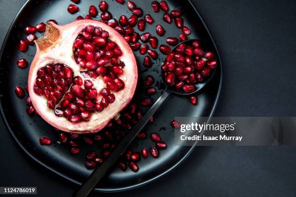 pomegranate half on plate - granaatappel stockfoto's en -beelden