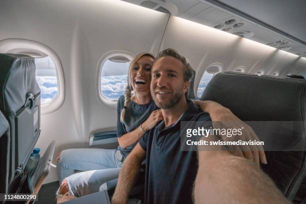 jong paar in de vlucht nemen selfie portret opgewonden om te gaan op vakantie - couple airplane stockfoto's en -beelden
