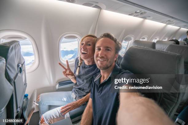 jong paar in de vlucht nemen selfie portret opgewonden om te gaan op vakantie - couple airplane stockfoto's en -beelden