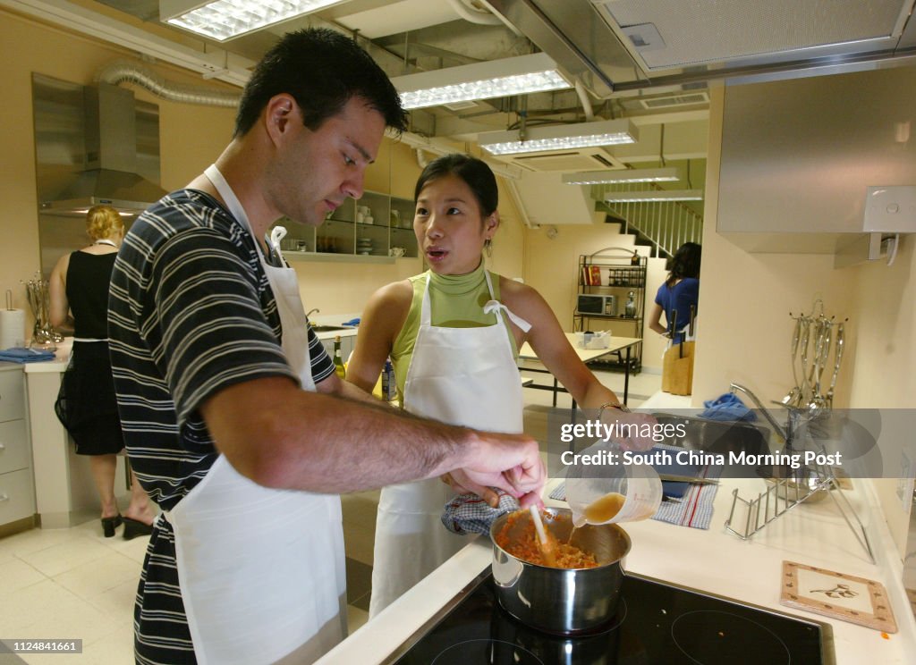 Couple Ernie Axeldank and Tang Mei-fong (green) cooking at the Appetite's new course that helps couples and corporations bond and team build through, at Po Yan Street, Sheung Wan.  03 July 2004