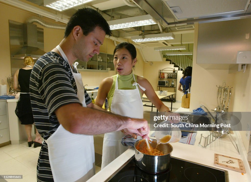 Couple Ernie Axeldank and Tang Mei-fong (green) cooking at the Appetite's new course that helps couples and corporations bond and team build through, at Po Yan Street, Sheung Wan. 03 July 2004