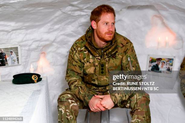 Britain's Prince Harry, Duke of Sussex, sits in a snow cave made by British military personnel and decorated with photos from his wedding on February...