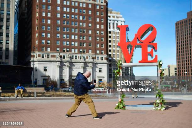 People are seen taking pictures for Instagram in front of a with bouquets of roses decorated LOVE Park statue, in Philadelphia, PA, on Valentines...
