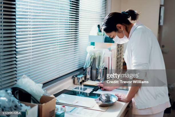 mid adult female nurse making notes in a hospital - preparing drug in hospital nurse stock-fotos und bilder