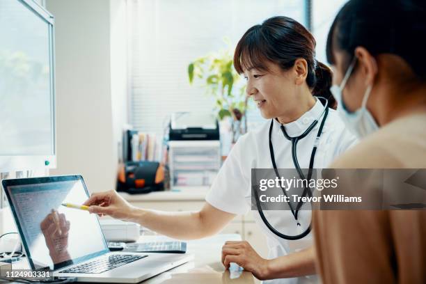 mature female doctor consulting with a teenage girl at a hospital - exame médico procedimento médico imagens e fotografias de stock