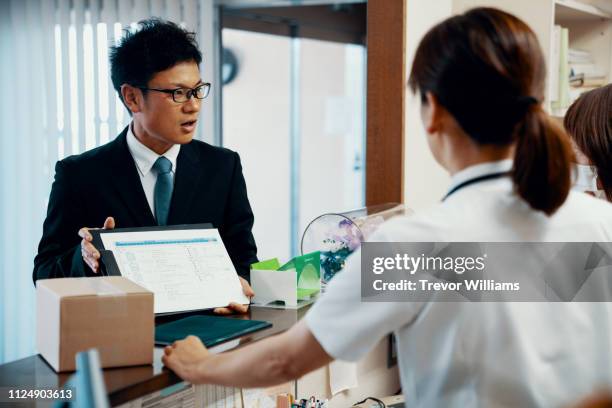 medical supply company executive meeting with a female doctor at a hospital reception desk - sales occupation ストックフォトと画像