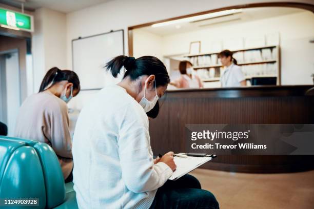 Mid adult woman filling out documents in a hospital waiting room