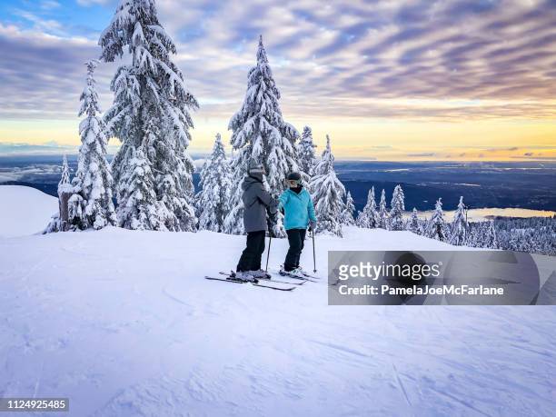 skifahrer am anfang der piste, blick auf den sonnenuntergang der stadt - family in snow mountain stock-fotos und bilder