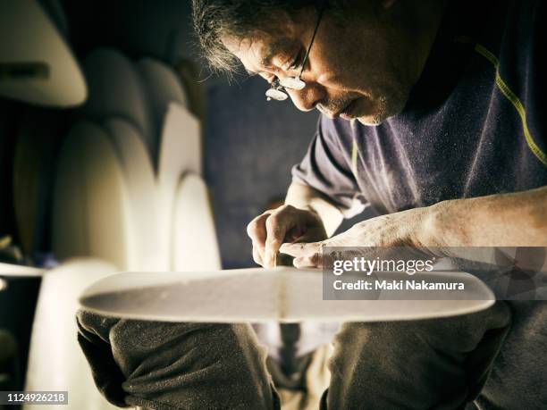 a senior male is shaping a surfboard - artisan 個照片及圖片檔