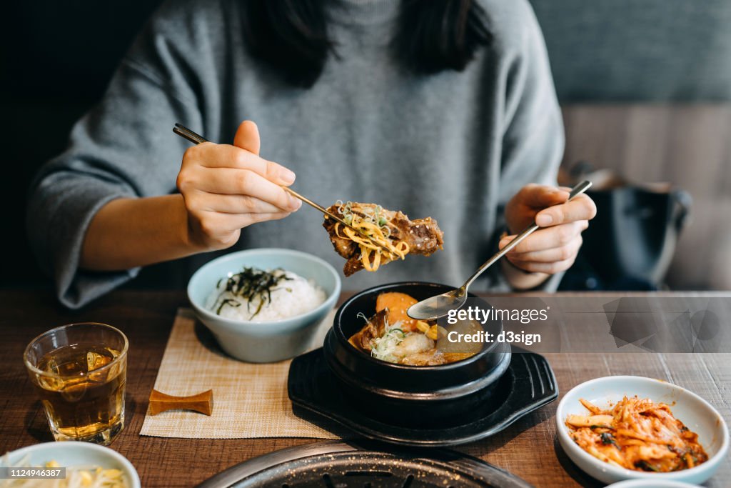 Woman enjoying Korean cuisine with a variation of traditional dishes in a restaurant