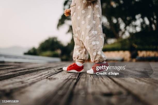 baby feet walking in wooden footpath in park - babyschuhe stock-fotos und bilder