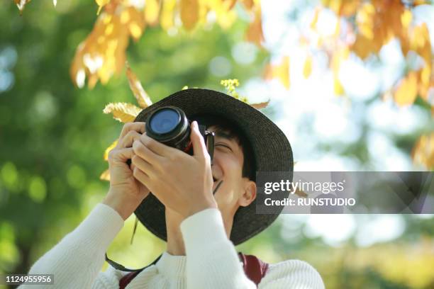 young man taking pictures with camera in park - japanese photographer photos et images de collection