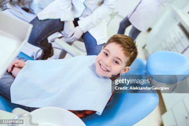 giovane ragazzo sorridente in posa prima del normale controllo dentale in clinica - dentista bambini foto e immagini stock