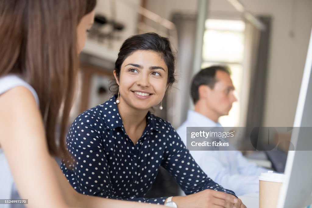 Multiracial colleagues communicating sitting in office at the desk