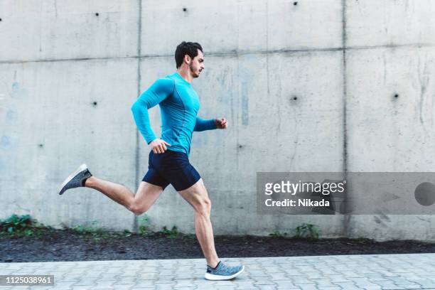 junger mann morgens im freien laufen - jogging stock-fotos und bilder