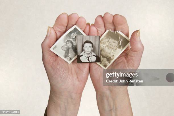 old lady's hands holding old photos - torn photograph stock pictures, royalty-free photos & images