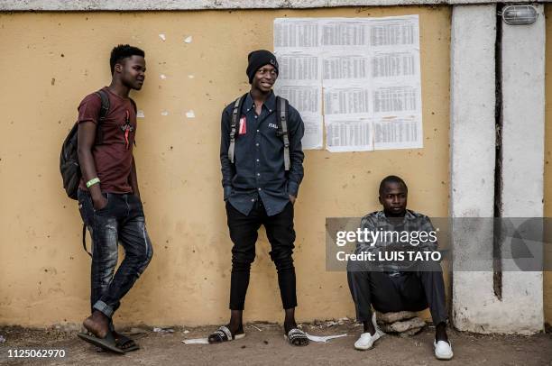 Three men stand in front of electoral lists at a polling station in Gombi, Adamawa State, Nigeria on February 15 one day ahead of the presidential...