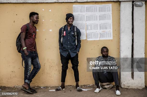 Three men stand in front of electoral lists at a polling station in Gombi, Adamawa State, Nigeria on February 15 one day ahead of the presidential...