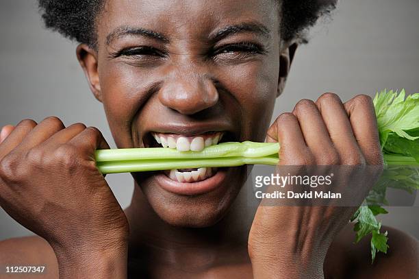 young black woman biting into celery - biting on something stock-fotos und bilder