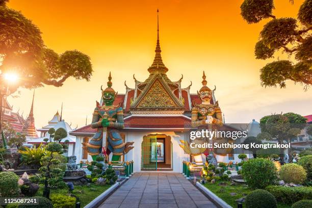 wat arun is a buddhist temple in bangkok yai district of bangkok, thailand. wat arun is one of famous landmark temple at sunset in bangkok thailand. giants front of the church at wat arun. - thailand stockfoto's en -beelden