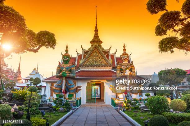 wat arun is a buddhist temple in bangkok yai district of bangkok, thailand. wat arun is one of famous landmark temple at sunset in bangkok thailand. giants front of the church at wat arun. - thailand stock pictures, royalty-free photos & images