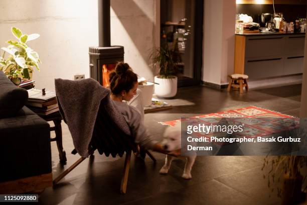 A woman petting her dog in front of a stove in a cozy living room