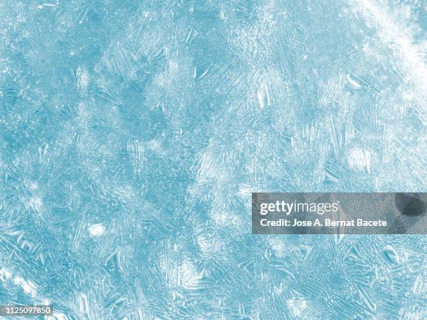 full frame of the textures formed of a block of cracked ice on a soft blue color background. - 氷　塊 ストックフォトと画像