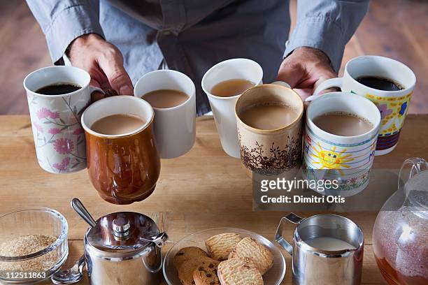man holding many tea and coffee cups - taza de café fotografías e imágenes de stock