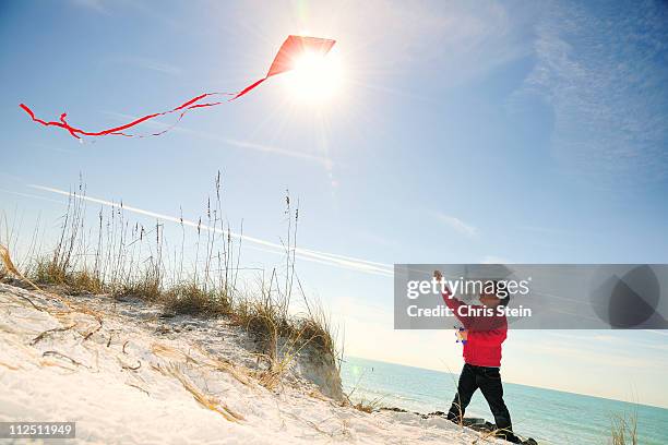 half asian young boy flying a red kite on beach - saia florida stock-fotos und bilder