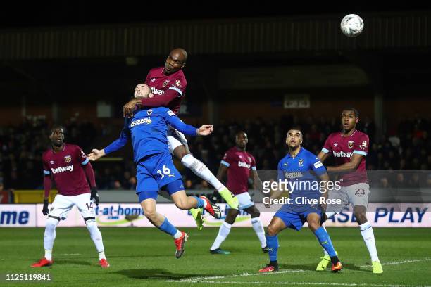 Dylan Connolly of AFC Wimbledon heads the ball under a challenge by Angelo Ogbonna of West Ham United during the FA Cup Fourth Round match between...