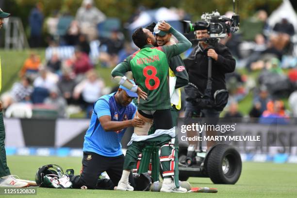 Bangladesh's Mohammad Mithun is attended to after injuring his leg during the second one-day international cricket match between New Zealand and...